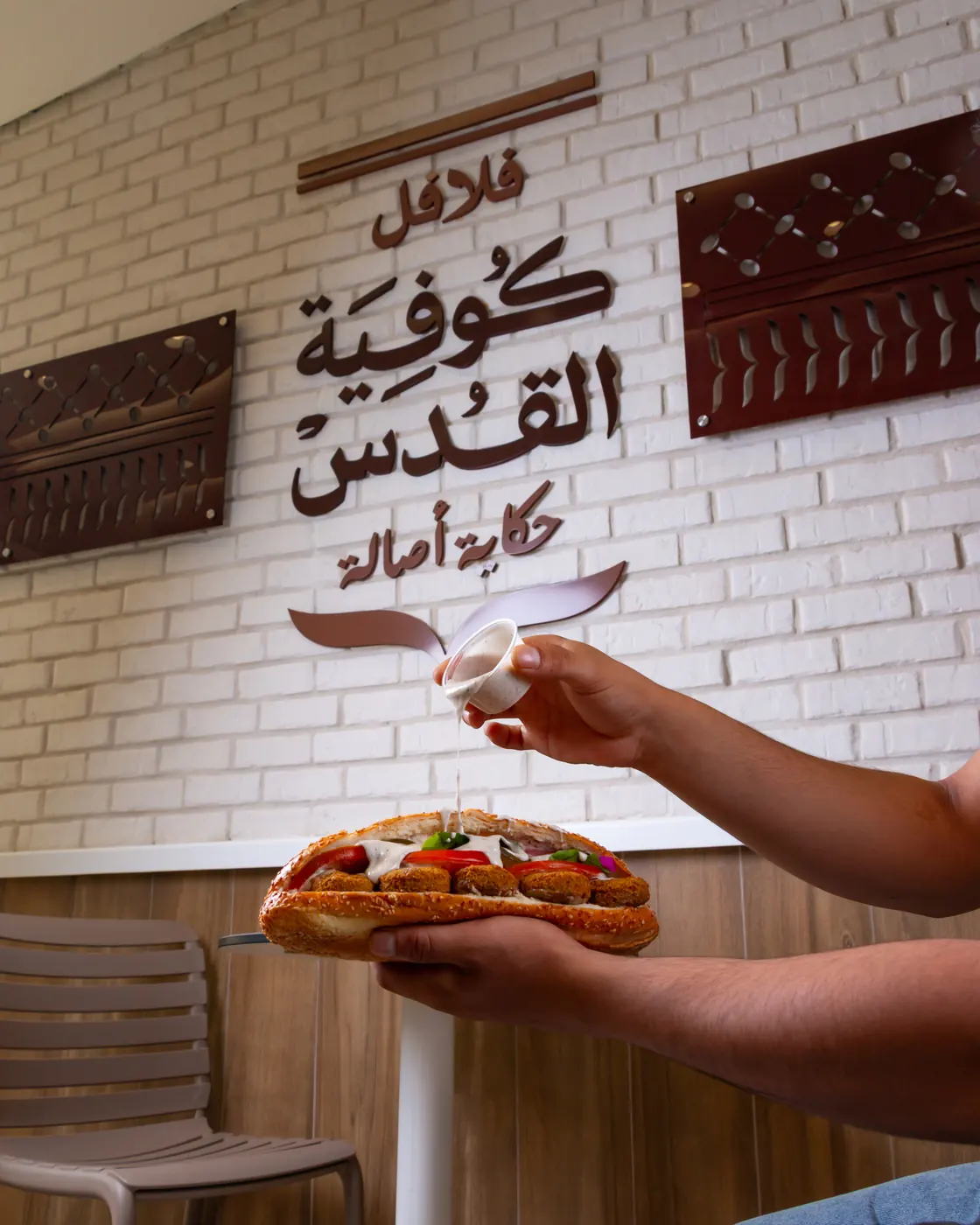 ساندويش أمام جدار شعار كوفية القدس